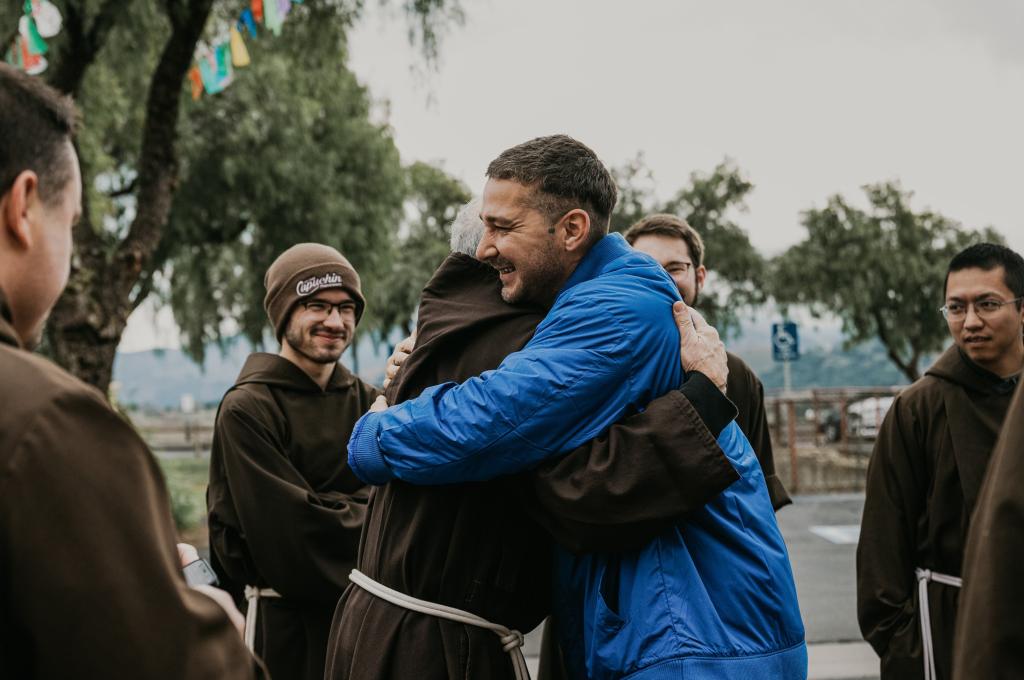 Shia LaBeouf hugs a friar.