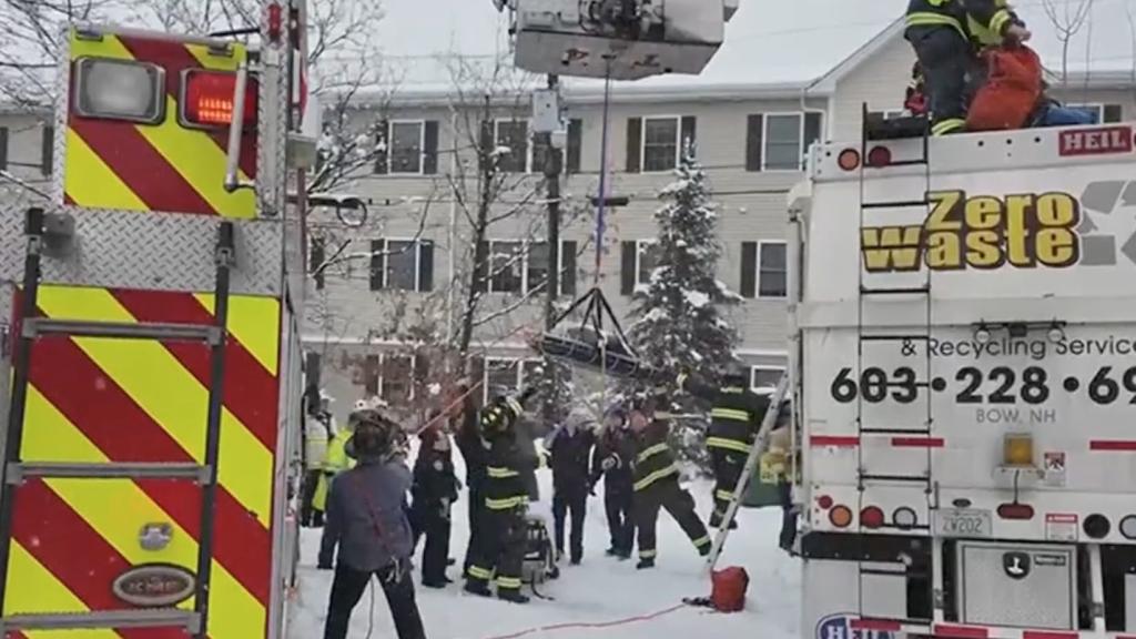 Firefighters grabbing the basket from the crane. 