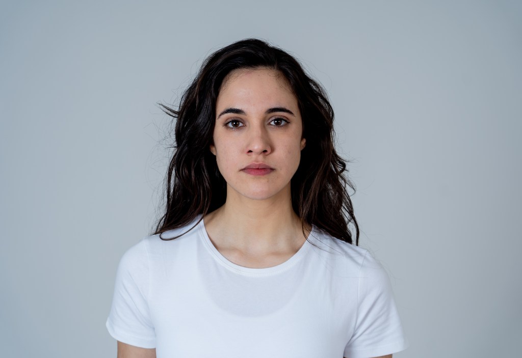 Close up of young attractive frustrated latin woman in stress with furious face. Looking mad and disappointed making angry gestures. In neutral background. In human facial expressions and emotions.