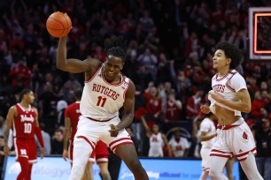 Clifford Omoruyi #11 spikes the ball as he and Derek Simpson #0 of the Rutgers Scarlet Knights celebrate their 87-82 overtime win over the Nebraska Cornhuskers.