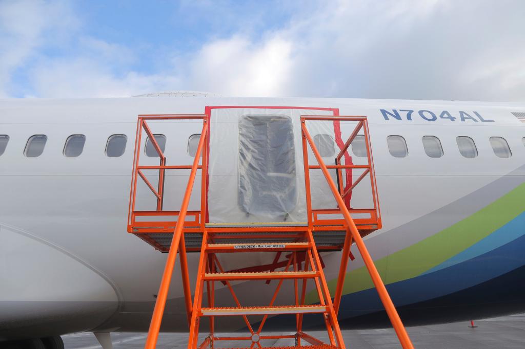 Plane seen with an orange staircase attached and plastic covering the door