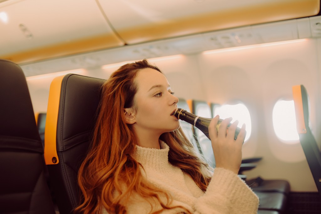 Woman drinking on a plane.