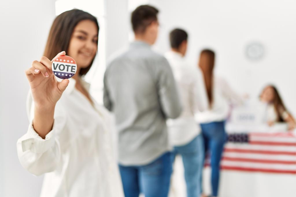 Young voter holding up a "Vote" pin