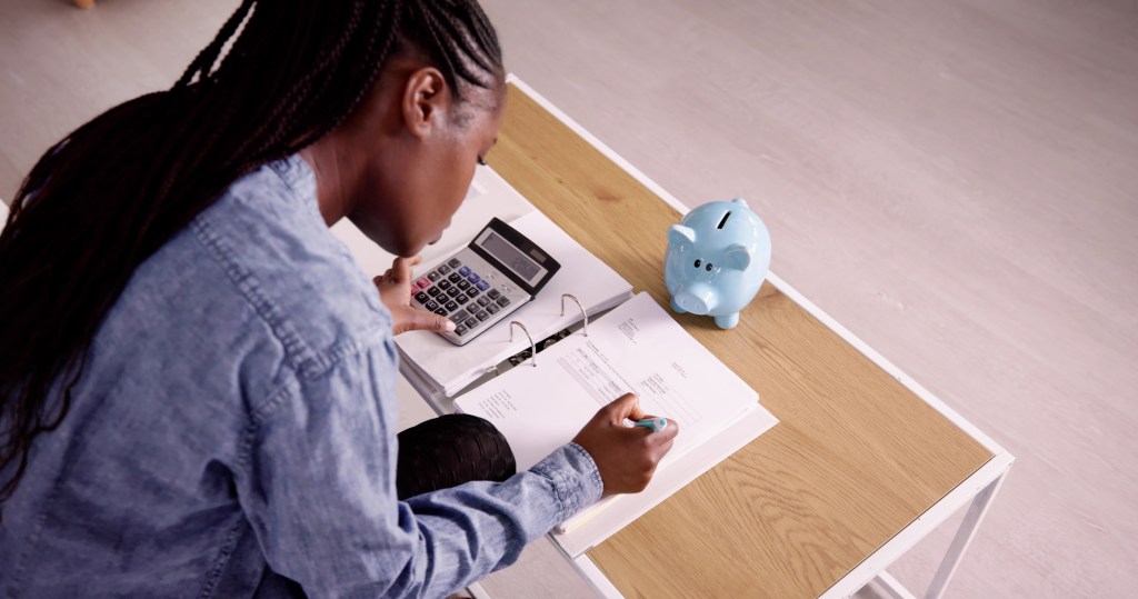 Young Woman Calculating Invoice With Calculator.