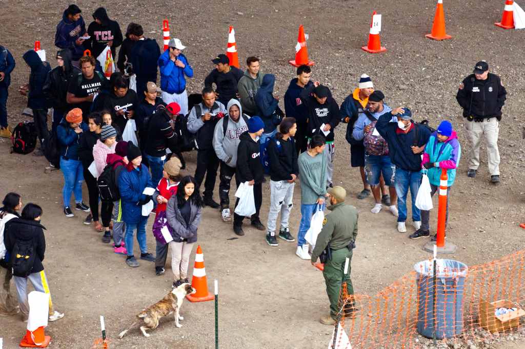 Migrants who crossed the Rio Grande river from Mexico cross into the United States surrender to U.S. Customs and Border Protection officers before they are transported to a migrant facility.