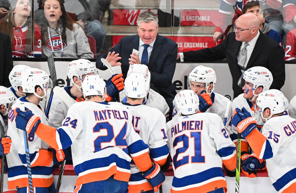 New York Islanders coach Patrick Roy, center, talks to players during the first period of the team's NHL hockey game against the Montreal Canadiens