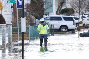 a utility worker tries to walk through the flooded streets.