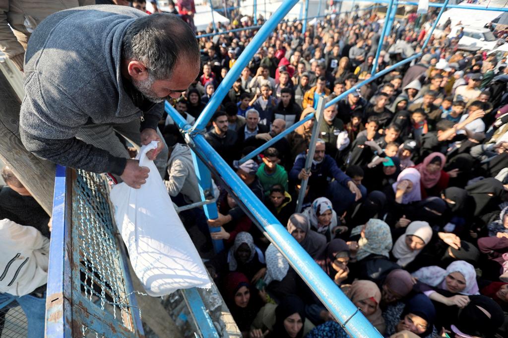 Hundreds of refugees wait to receive flour and supplies from UNRWA workers in Gaza. 