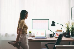 Woman stretching her legs standing next to her desk