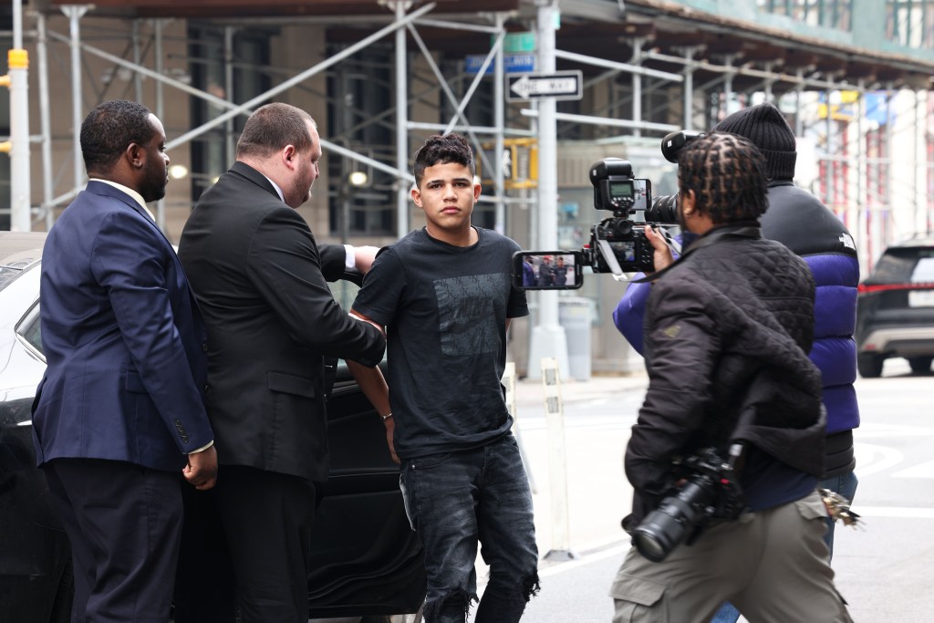 15 year old Venezuelan male in handcuffs being escorted into a courthouse by police officers for charges of shooting a woman in NYPD station