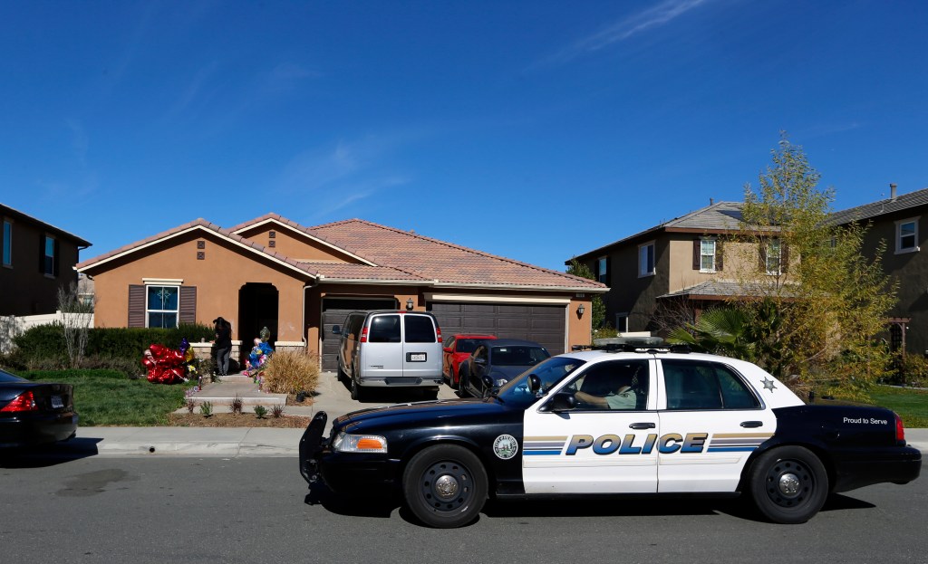 FILE - A police car drives past the home of David and Louise Turpin where police arrested the couple accused of holding 13 children captive on Jan. 24, 2018, in Perris, Calif. A report released Friday, July 8, 2022, says the social services system "failed" the 13 children who were rescued after being starved, shackled to beds and horribly abused by their parents the Turpin's at their Southern California home for years. 