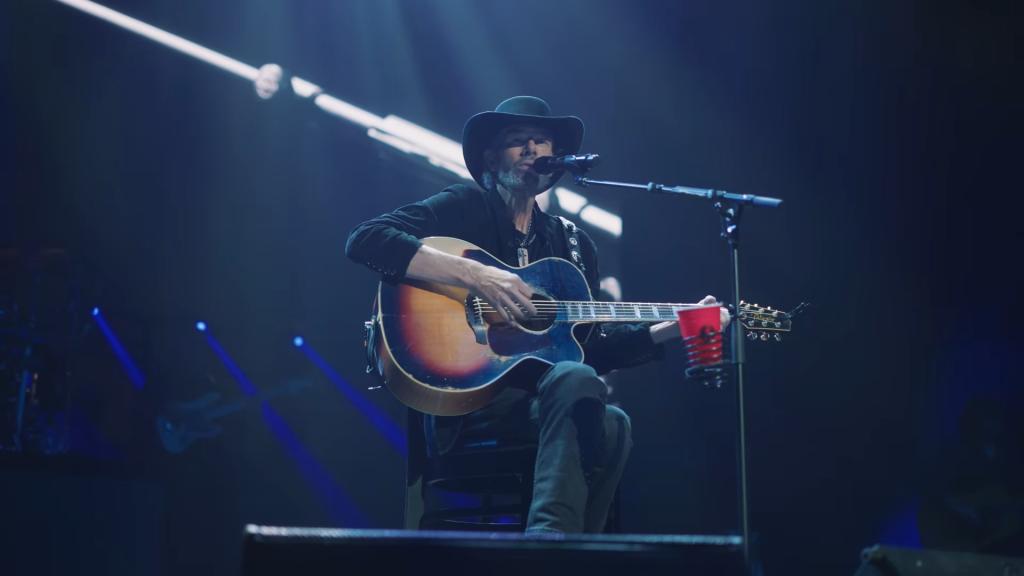 Toby Keith playing guitar and singing into a microphone on stage in Las Vegas during a December 2023 performance.
