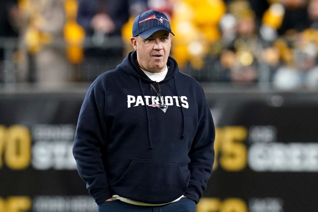 A man in a hoodie watching warmups for a football game between the New England Patriots and Pittsburgh Steelers.