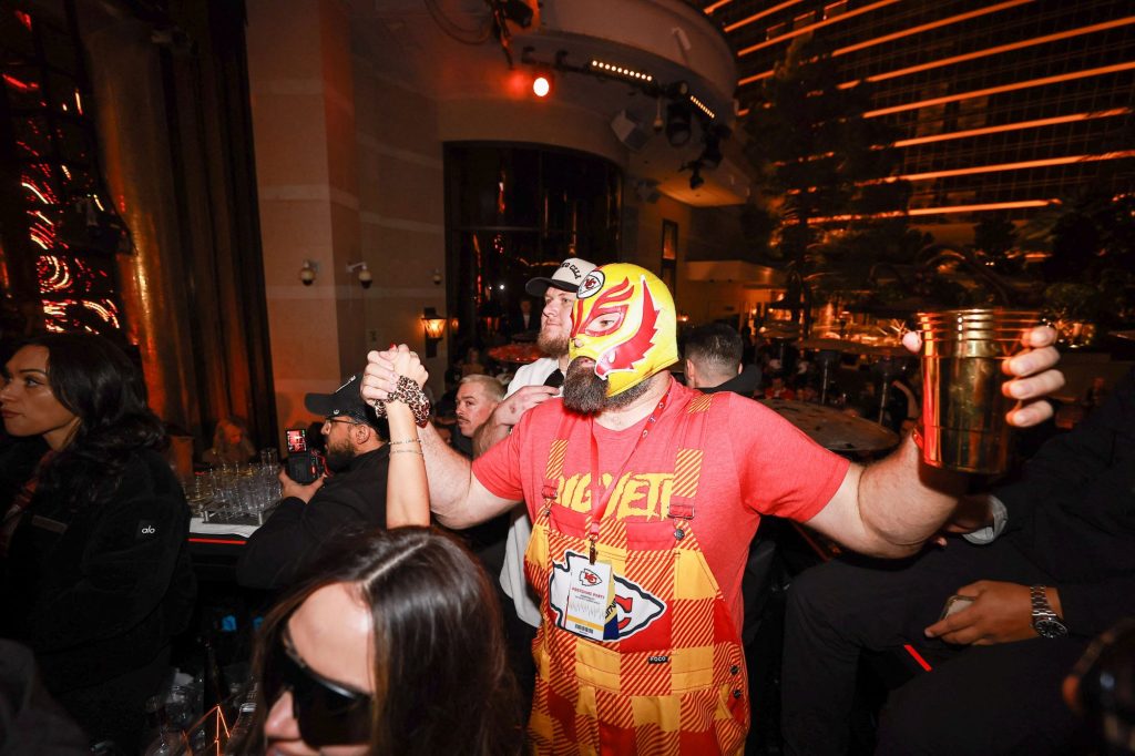 Jason Kelce wearing a lucha libre wrestling mask celebrates the Kansas City Chiefs' Super Bowl win at XS Nightclub at Wynn Las Vegas in a crowd.