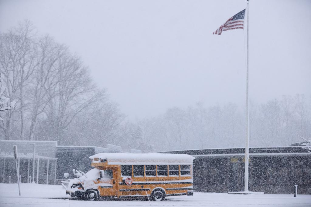 A school bus is covered in snow at a school 