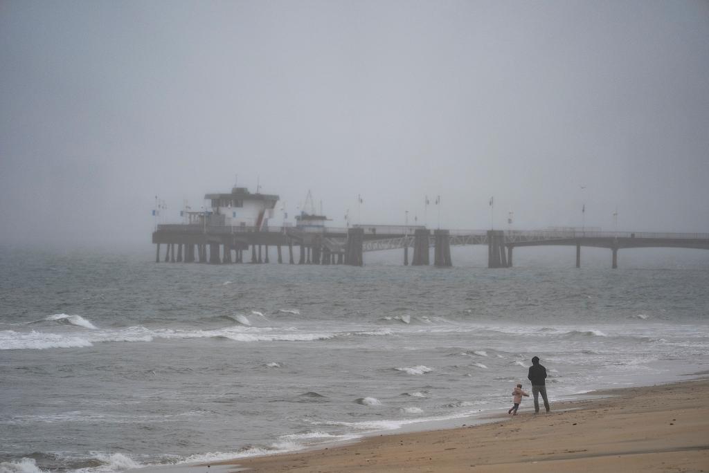 People on the beach during a storm brought by an atmospheric river in Long Beach, California on Feb. 19, 2024.