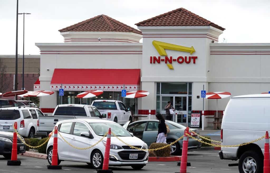 An In-N-Out Burger restaurant with cars parked in front of it on a street in Oakland, California.