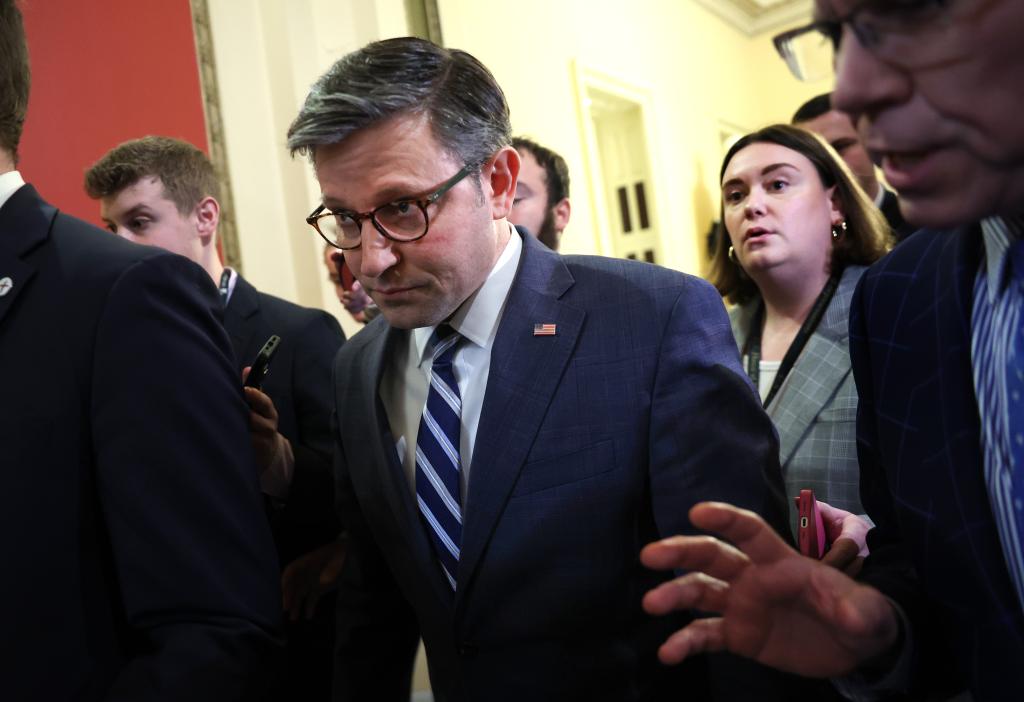 A man in a suit and tie talking to reporters as he returns to his office at the U.S. Capitol.