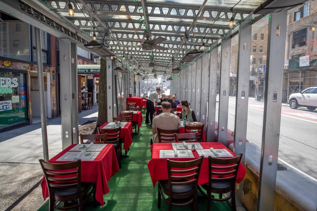 Tables and chairs, with seated diners, inside Donohue's outdoor dining shed