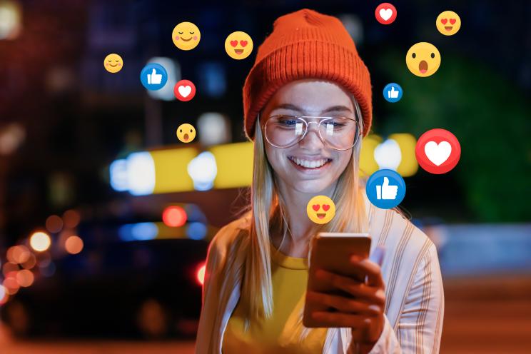 A woman using a smartphone while getting emotional reactions on social media.