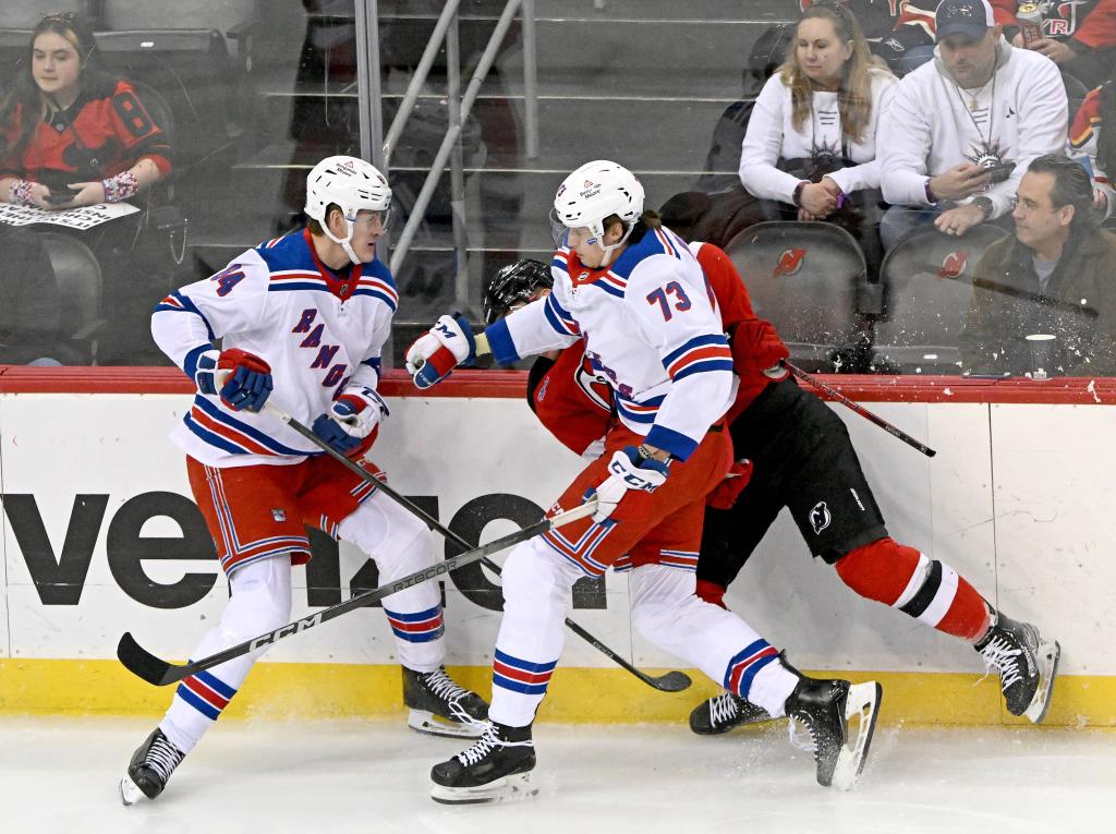 Matt Rempe #73 of the New York Rangers checks Nathan Bastian #14 of the New Jersey Devils into the boards and receives a match penalty