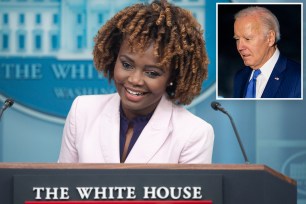 White House Press Secretary Karine Jean-Pierre speaking at podium with a smile and reporters in the background.