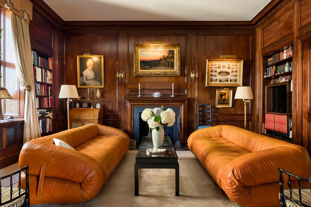 Living room with two caramel leather sofas and wood paneled walls