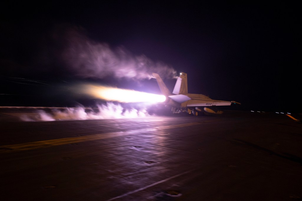 A fighter jet taking off from USS Dwight D. Eisenhower during night flight operations in the Red Sea to strike Yemeni Houthi targets.