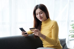 A woman using her phone to shop online with her credit card.