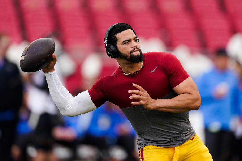 Southern California quarterback Caleb Williams warming up with a football before a game, with other players in the background.