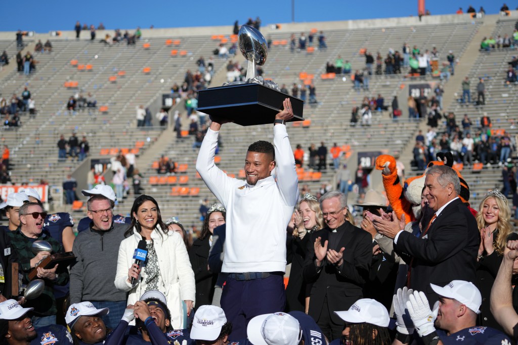 Notre Dame head coach Marcus Freeman holds the championship trophy after the Sun Bowl college football game against the Oregon State Beavers.
