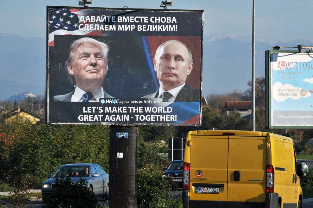 Cars pass by a billboard showing US President-elect Donald Trump and Russian President Vladimir Putin.
