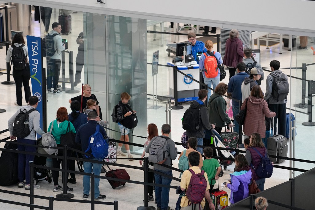 Group of people standing in a line at Nashville International Airport, waiting to go through security checkpoint for holiday travel.