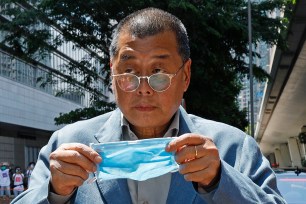 Hong Kong media tycoon Jimmy Lai, who founded local newspaper Apple Daily, prepares to put on a face mask before entering a court in Hong Kong.