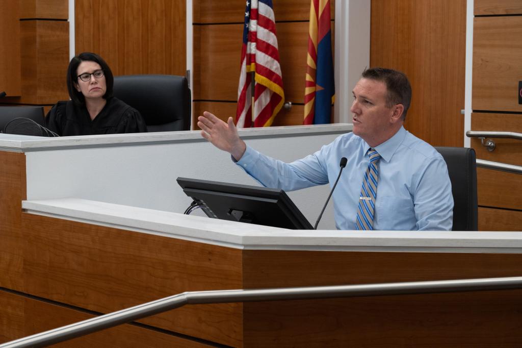 Surprise Police Department Detective Jeremy Goebel (right) answers a question during the hearing for Raad Almansoori on Feb. 26.