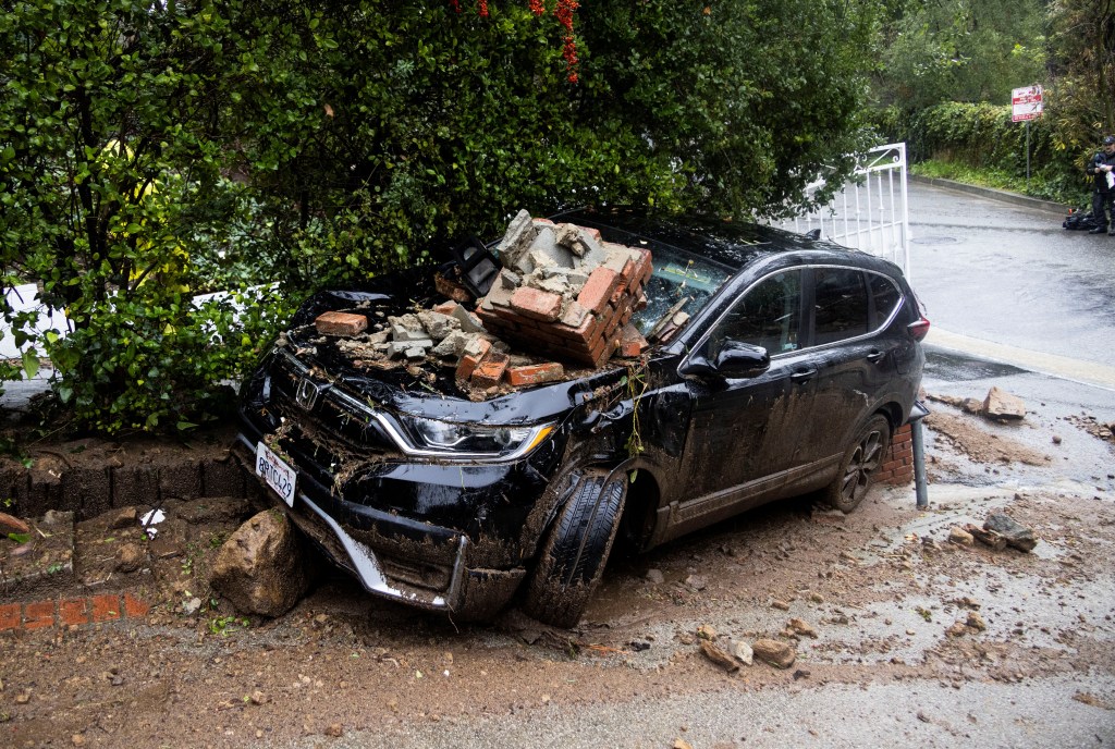 Bricks lie on top of a damaged car, during the ongoing rain storm