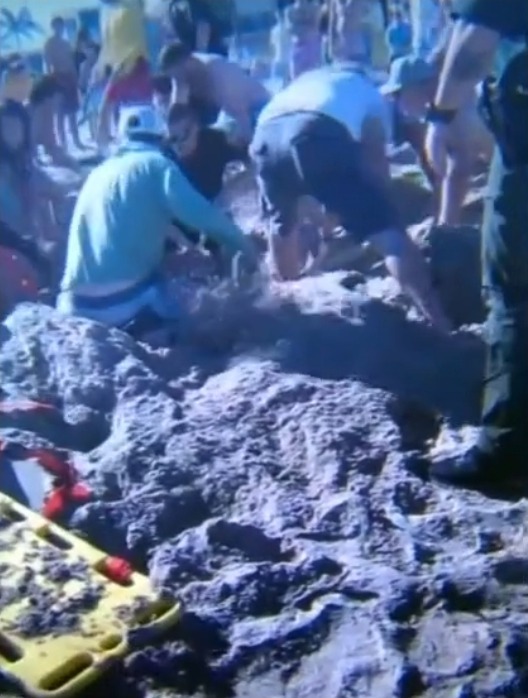 Beachgoers and rescue works dig frantically to save the girl after the sand caved in on her.