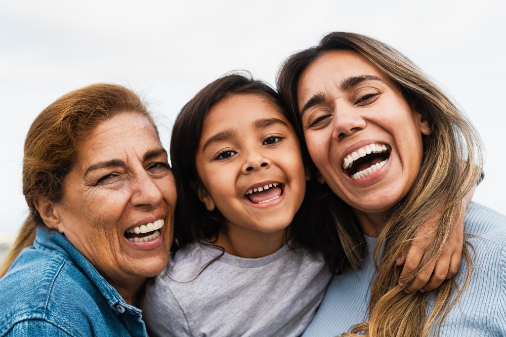 Hispanic multigenerational family and a child smiling for the camera outdoors.