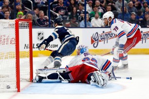 Columbus Blue Jackets forward Jack Roslovic, left, scores past New York Rangers goalie Jonathan Quick, center, and defenseman K'Andre Miller during the second period of an NHL hockey game in Columbus, Ohio on Sunday.