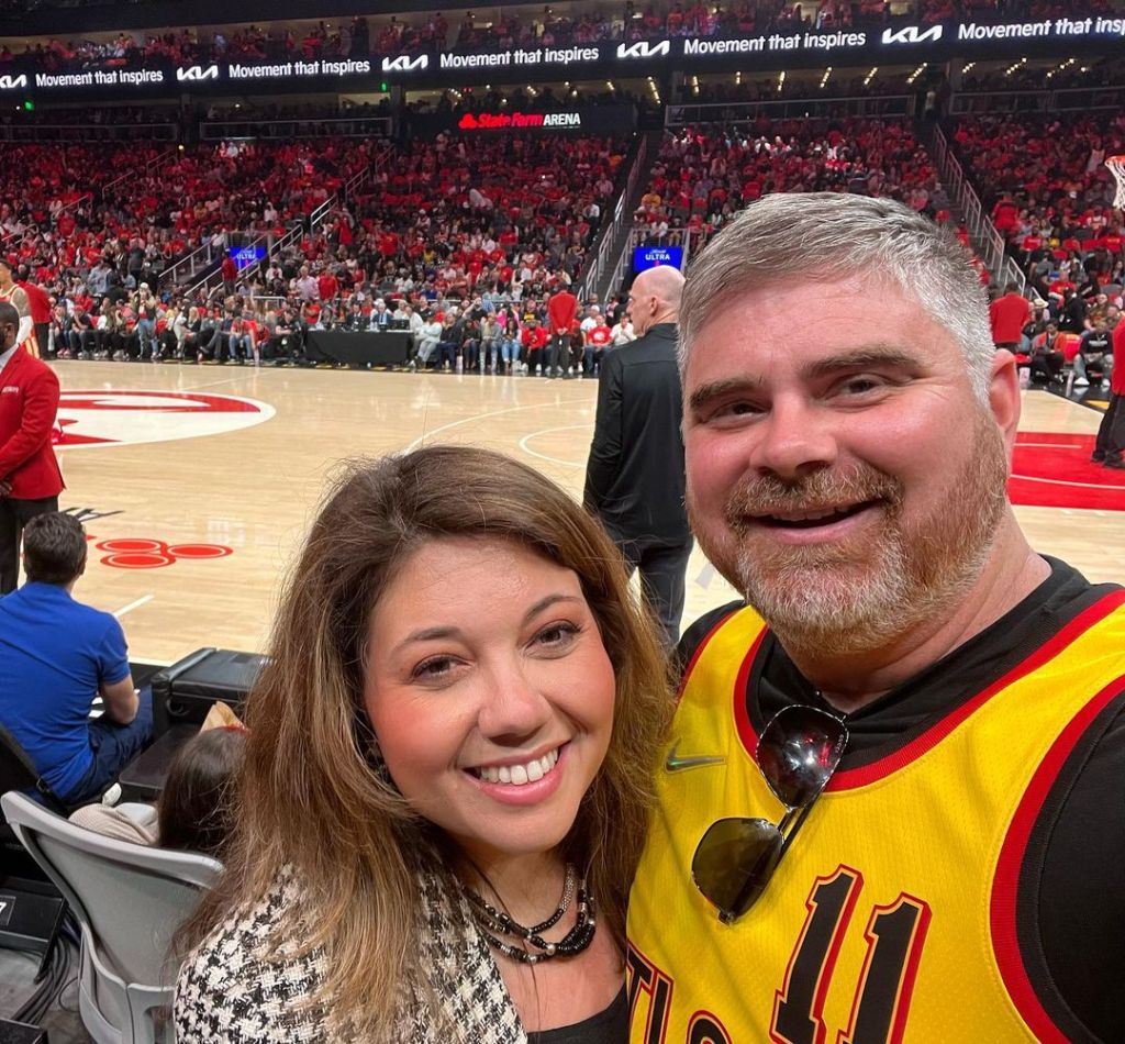 Ben Armstrong and wife Bethany at basketball game, seen taking social media selfie