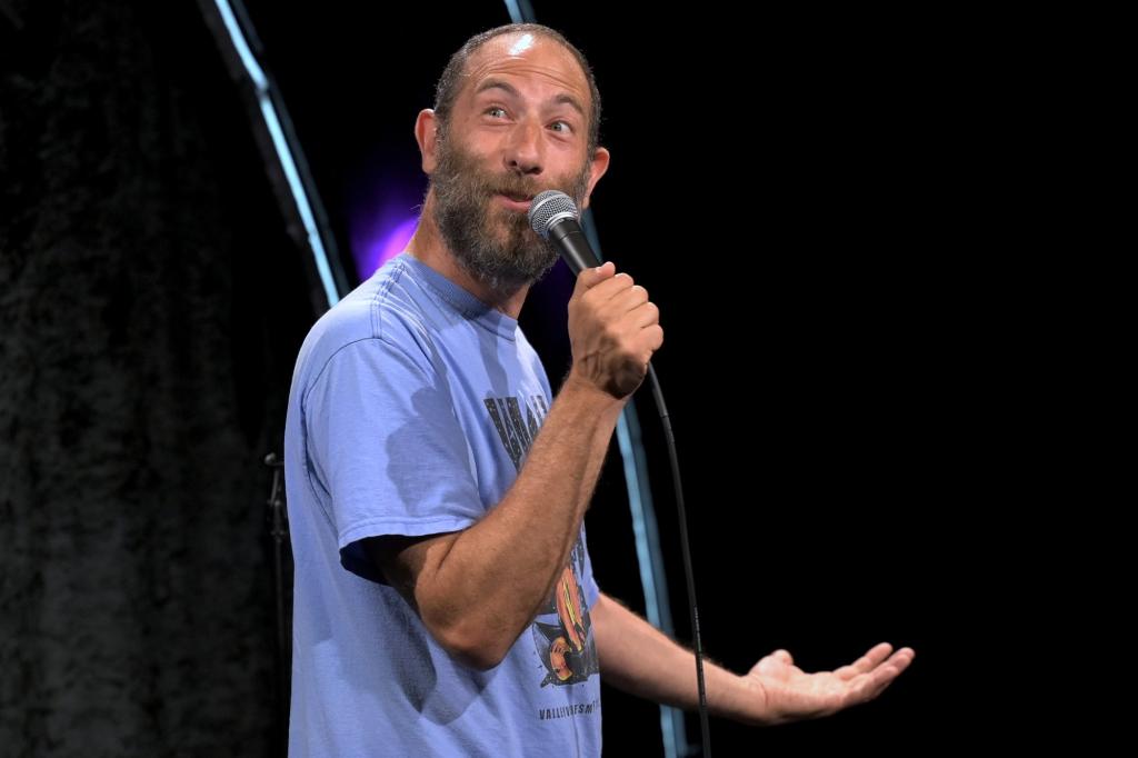 Ari Shaffir, a man with a microphone on stage.