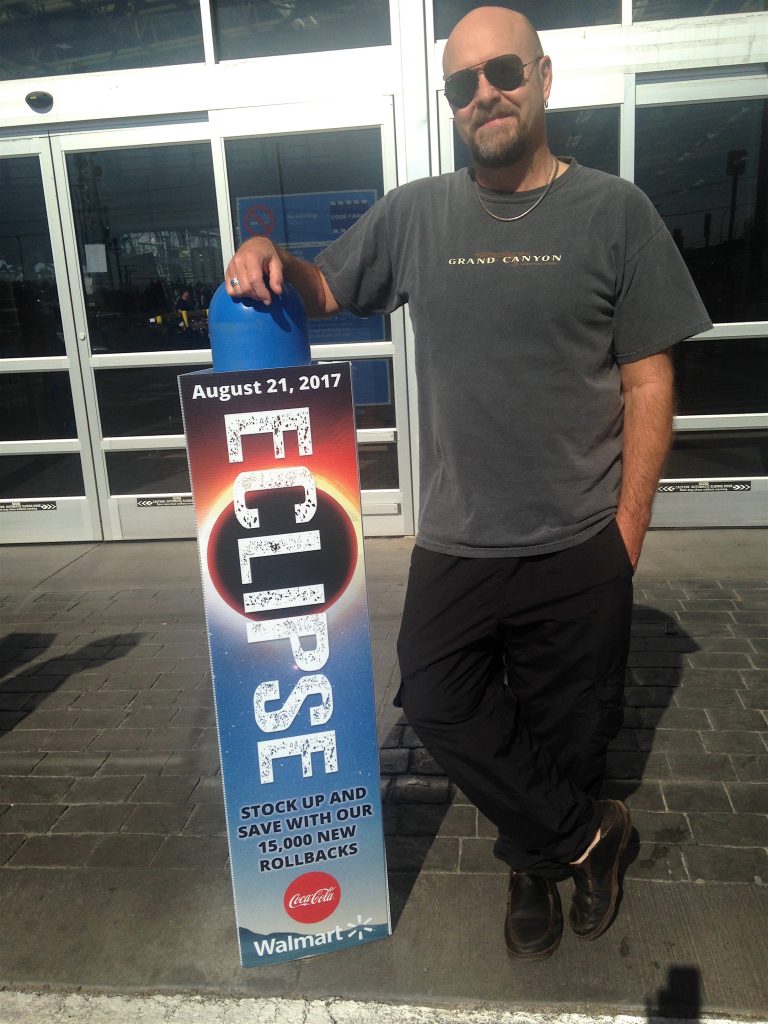 David Makepeace posing alongside an eclipse sign from 2017