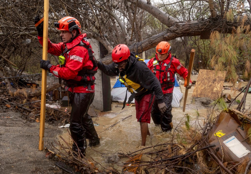 Firefighters rescue a man from a homeless encampment that became surrounded by floodwater 