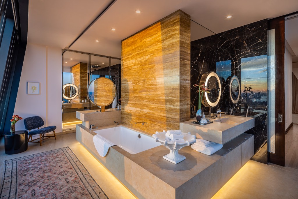 Bathtub wit marble surround and a wood accent wall