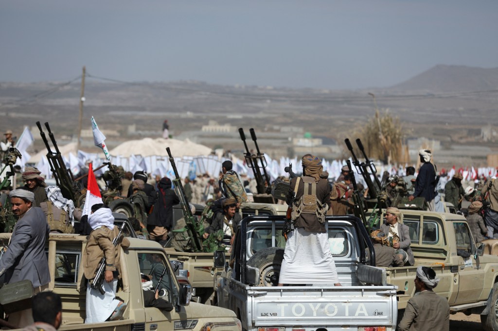 Houthi tribesmen parade with guns in military uniforms, showing defiance after US and UK air strikes on their positions near Sanaa, Yemen.