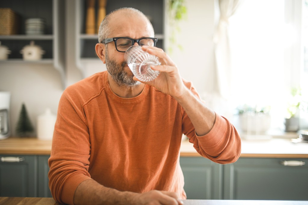 Mature adult man drinking water.