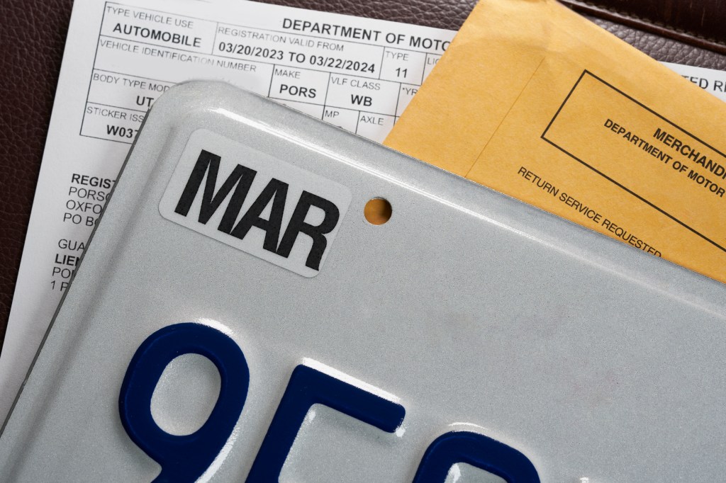 License plate registration documents and envelope on leather surface. DMV USA. 