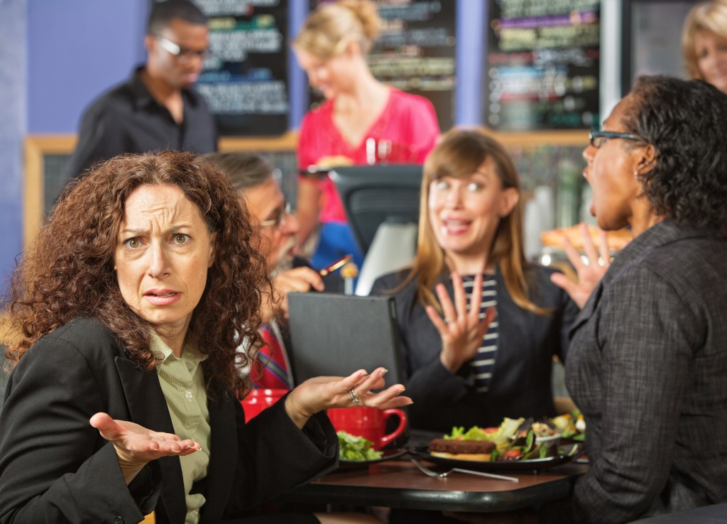 Irritated business woman with coworkers in cafeteria