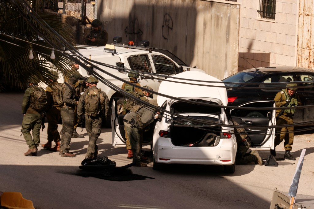 Israeli security forces check a car that was reportedly used by a Palestinian to carry out a thwarted ramming attack against troops positioned near the settlement of Kiryat Arba.