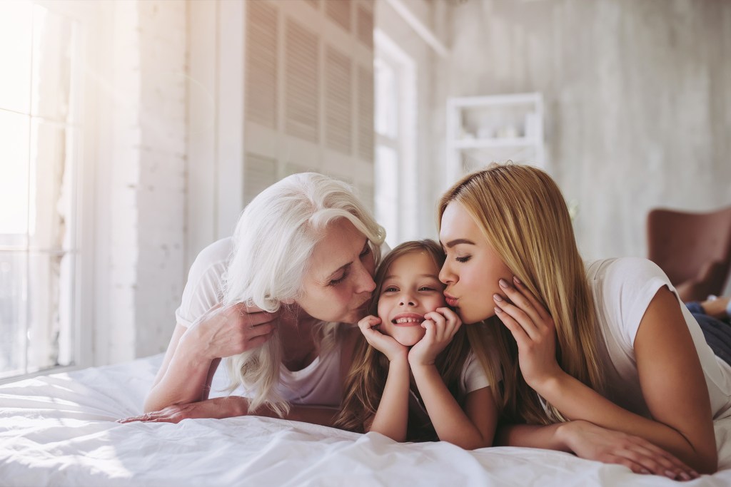 Three generations of women lying on bed together, celebrated on International Women's Day and Mother's Day.